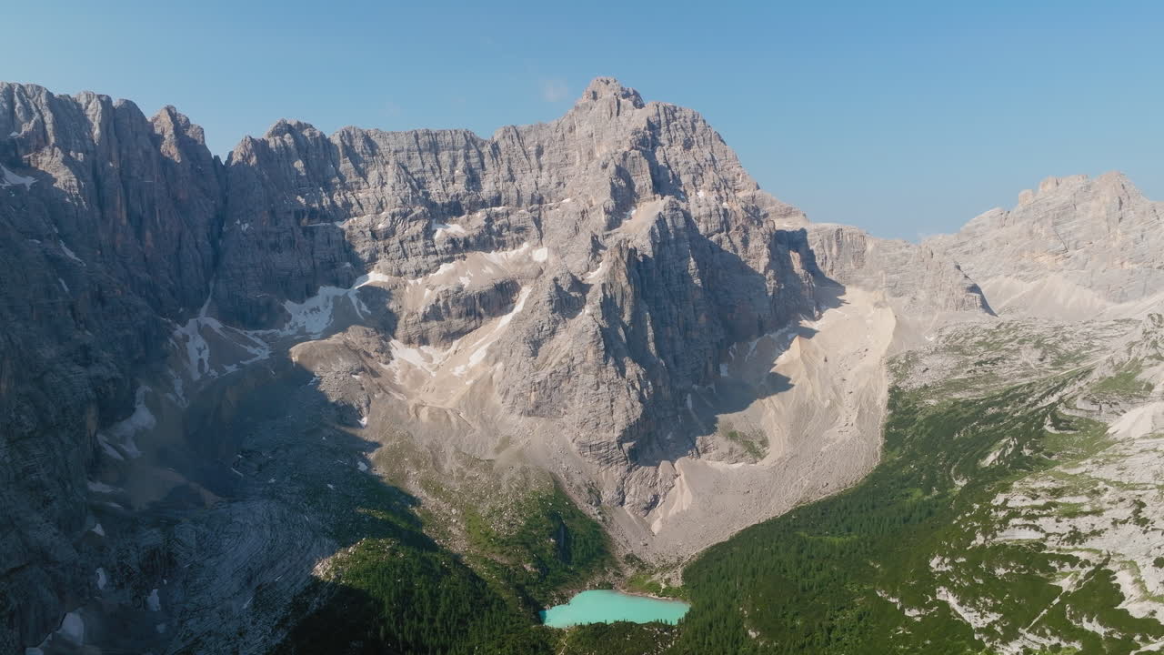 Aerial view of Lake Sorapis in the Italian Dolomites during spring, featuring its iconic turquoise waters surrounded by awakening alpine landscapes