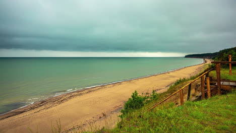 Zeitraffer-Eines-Strandes-Mit-Dunklen-Wolken-über-Der-Küste,-Wellen,-Die-An-Einem-Regnerischen-Nachmittag-Am-Ufer-Krachen