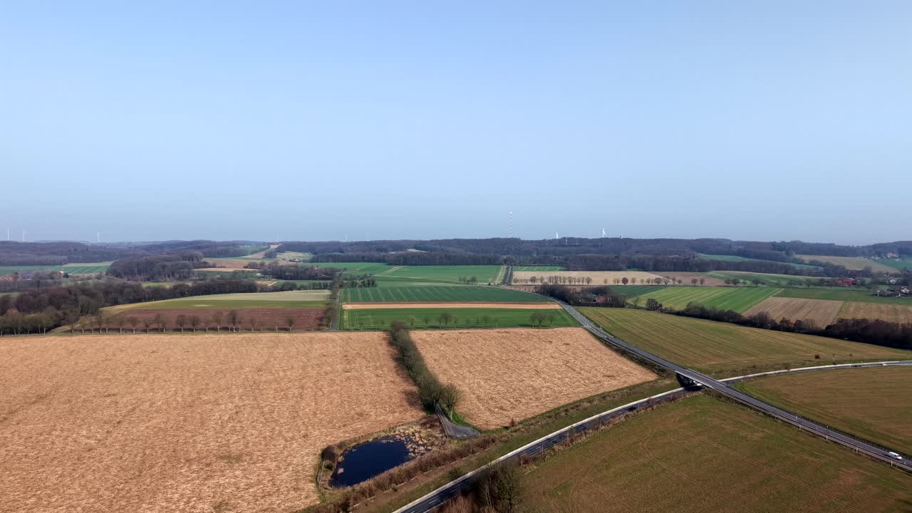 Aerial drone view of rural farmland in spring with colorful agricultural fields, country road intersection and open countryside landscape under clear sunlight in United States. Wide shot