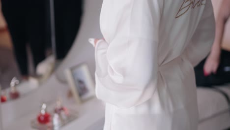 bride tying the belt of her white robe as she gets ready for the wedding ceremony