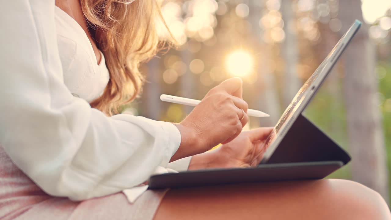 Woman sketching on a tablet with a stylus pen in the park