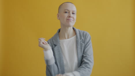 bald woman dancing in grey blazer