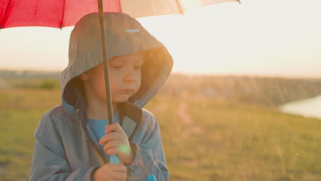 sad boy clutches umbrella tightly in field small child expression mirrors heaviness of rainfall on