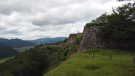 lush hilltop of takeda castle overlooking edge of mountain valley, ruins of ancient japanese fortress