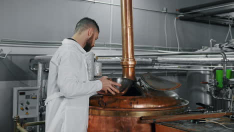 brewery worker inspecting copper brewing vessel