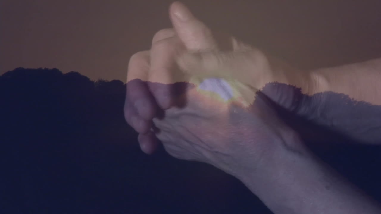 Clasping hands over mountain silhouette during sunset, creating animation effect