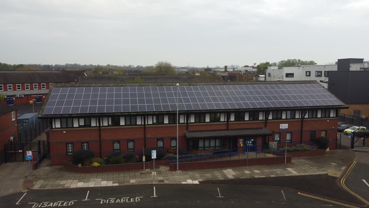 Politistation i Widnes by med tag med solpaneler til vedvarende energi i bybilledet i Cheshire, luftfoto der stiger op og vipper ned