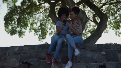 two mixed race women taking picture in park