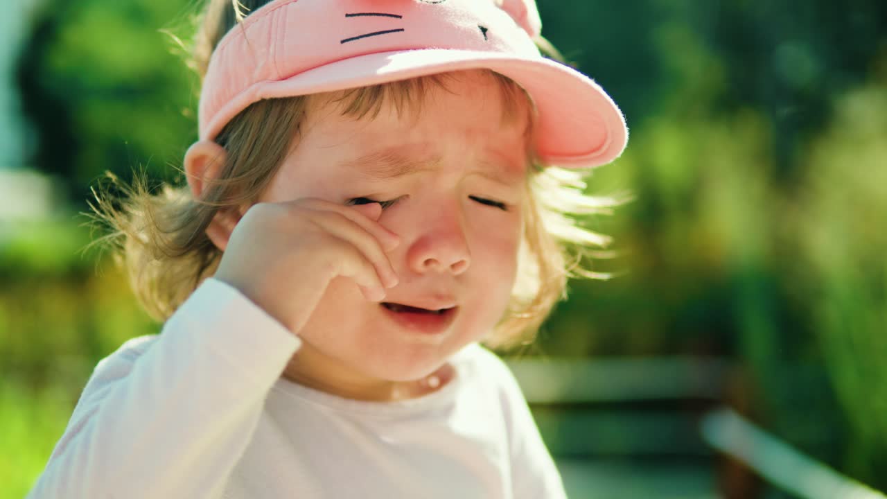 The child cries a lot rubbing eyes outdoors