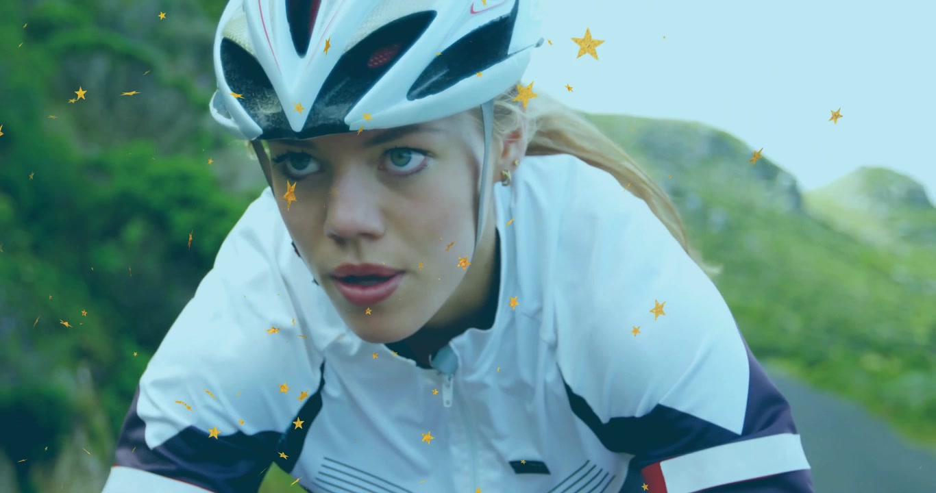 Cyclist rounding bend on winding mountain road generating drifting star particles enhancing fitness