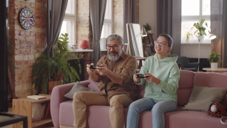 happy father and daughter playing console game at home