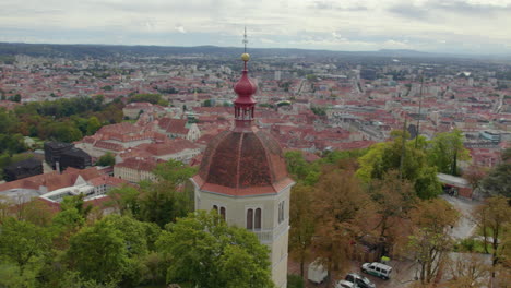 vista aérea cerca de la órbita alrededor de la histórica torre glokenturm en la cima de una colina en el schloßberg de graz con vistas a la ciudad