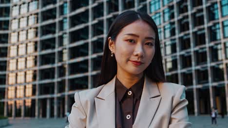 young businesswoman standing with arms crossed, exuding confidence and professionalism against backdrop of a modern office building, showcasing ambition and success in corporate world