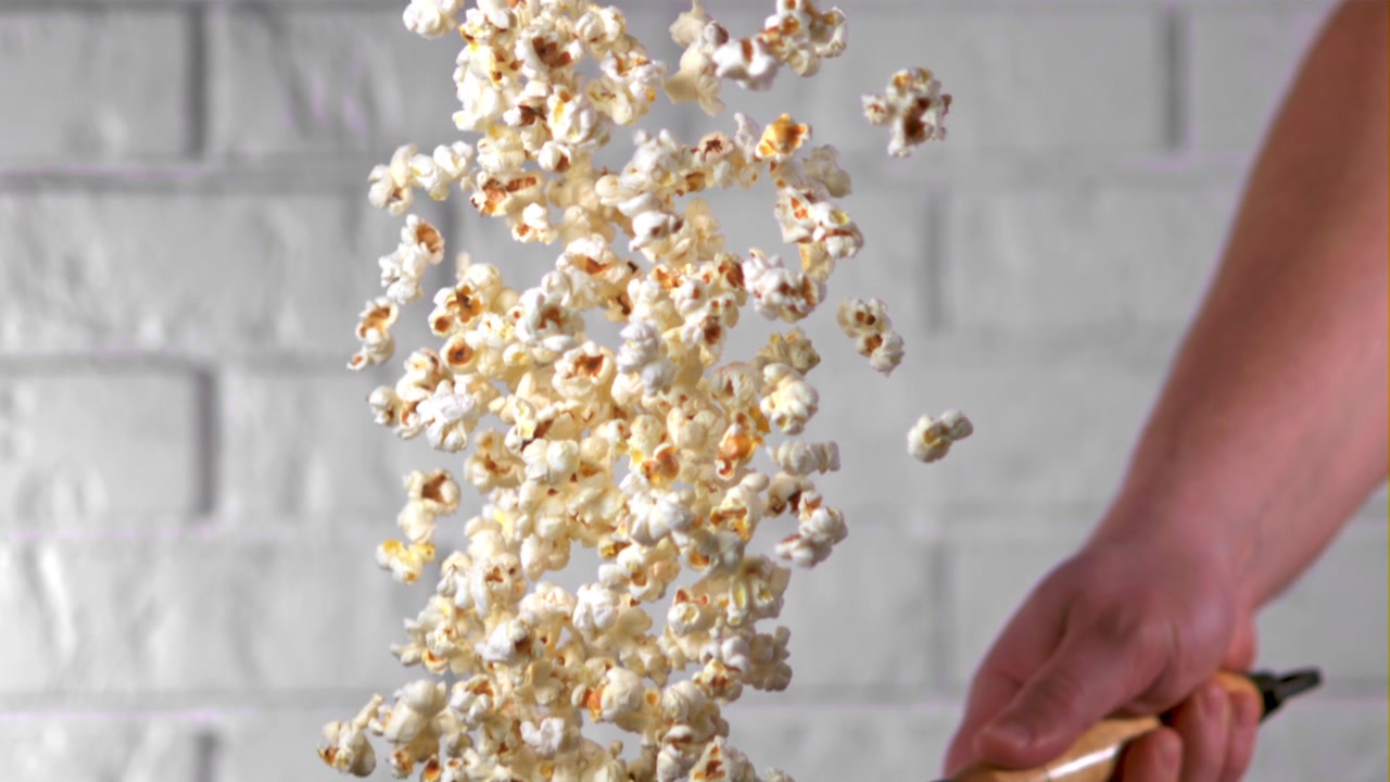 Sakte film av popcorn som kastes fra en stekepanne.