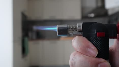 Male-hand-turn-on-a-gas-lighter-in-the-kitchen,-blue-flame