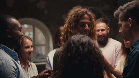 a curly man with light brown hair in a green jacket with his eyes closed is relaxed and is being spun in a circle by participants in group therapy. practice of trust and mutual assistance in group therapy