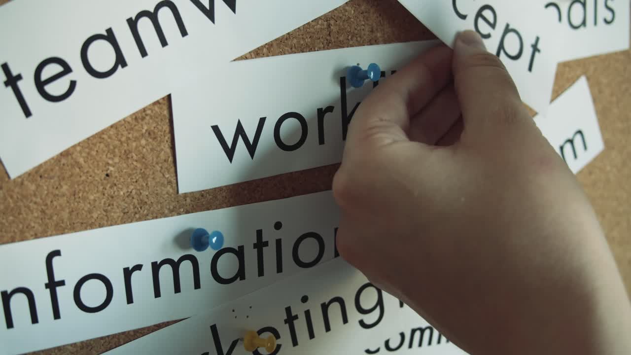 Sticky notes: TEAMWORK, SUCCESS, WORKFLOW, BRAINSTORM, INFORMATION, CONCEPT, COMMUNICATION, MARKETING, IDEAS - Pinned to cork wall