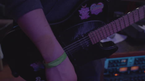 close up of a lead guitar player playing a riff on a six string electric guitar while his band is recording in a professional recording studio