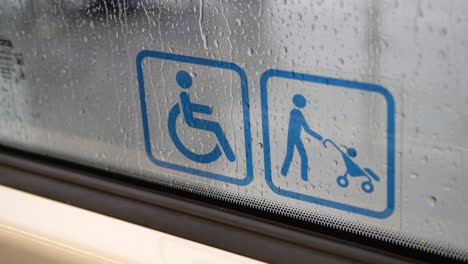 wheelchair and stroller accessibility signs on a wet window