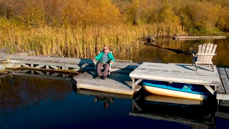 man sitting on dock at sunset