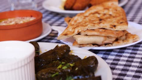 vista de cerca a través de pan plano recién horneado apilado en un plato en la mesa junto con otros platos con salsas