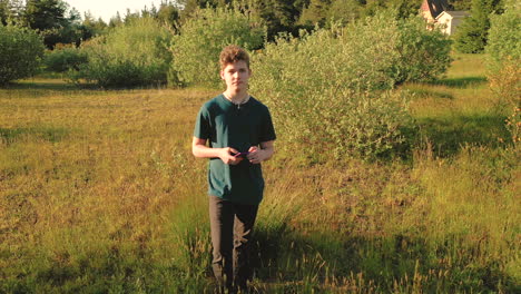 Drone-flying-towards-teen-who-is-holding-a-smart-phone-in-his-hand