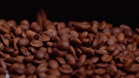 falling brown roasted coffee beans in professional studio lights and black background