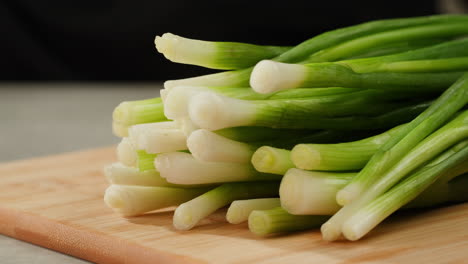Cutting fresh green onions on a cutting board, close up chef cooking green vegan salad.