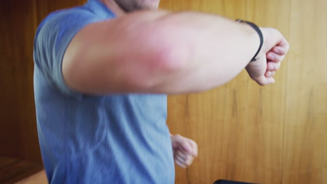 close up of man exercising on treadmill checking smart watch