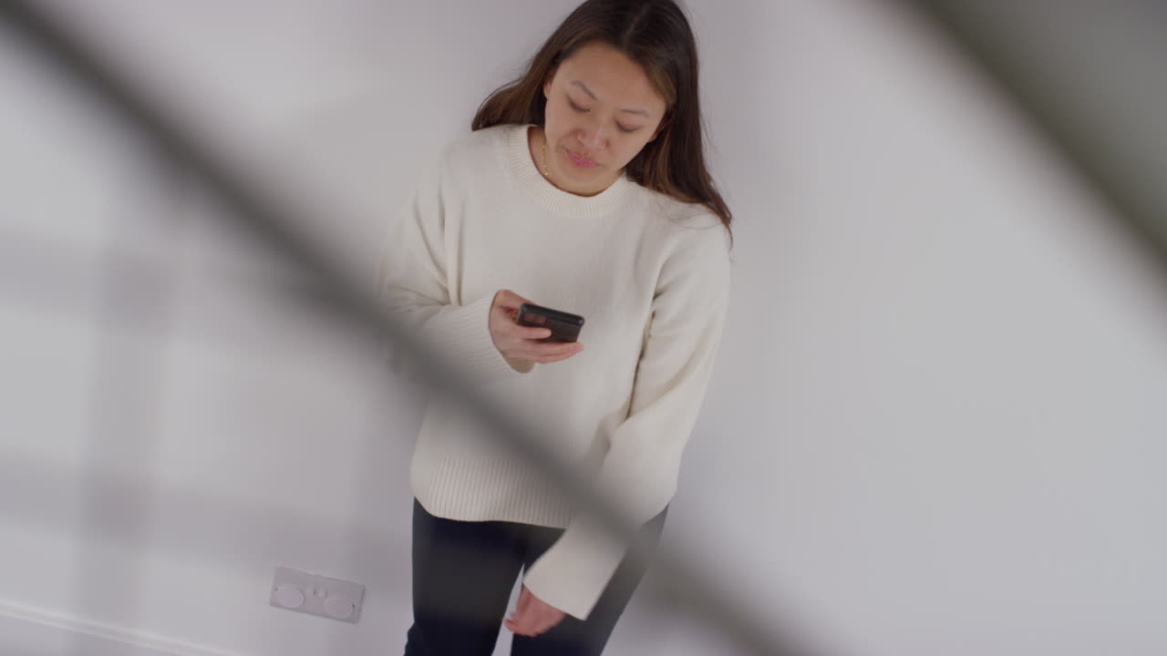 스트레스를 받거나 불안한 여성이 집에서 벽에 기대어 인터넷이나 소셜 미디어 뉴스 메시지 또는 휴대 전화에 반응하는 오버헤드