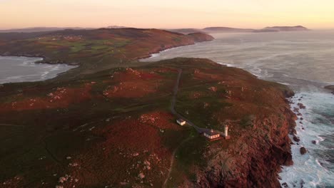 Lighthouse-building-complex-on-Spanish-rocky-coastline,-high-angle-drone-view