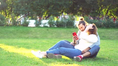 pareja relajándose en el parque con un teléfono inteligente