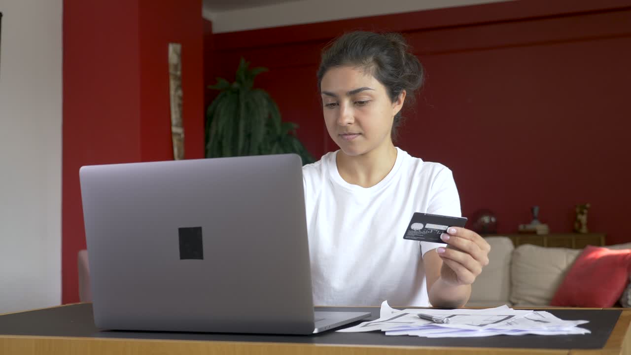 una mujer india feliz escribe el número de tarjeta de crédito en su portátil y compra en línea. un adicto a las compras compra en internet.