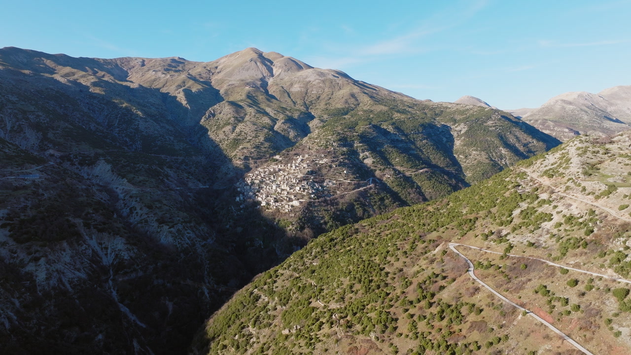 Panoramic drone shot of Syrrako village in Tzoumerka, Epirus, Greece on a sunny day and surrounded by rugged mountains