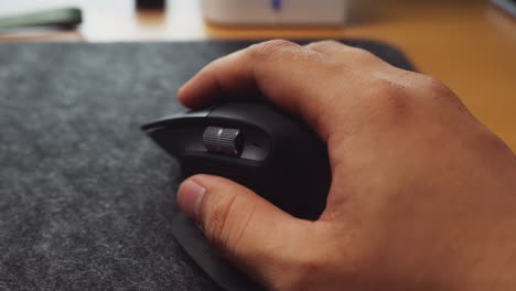 close-up hand using black wireless mouse on cloth mousepad