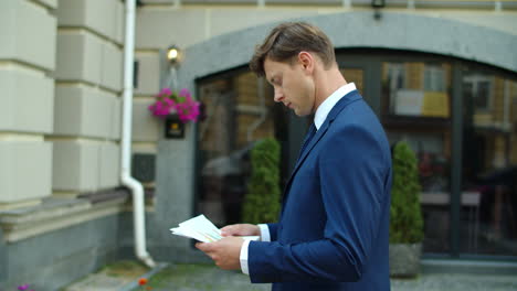 Pensive-business-man-reading-documents-durink-walk-outdoors