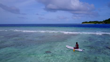 young man exploring shallow lagoon paddling with canoe around turquoise waters close to white waves coming from deep blue sea in malaysia