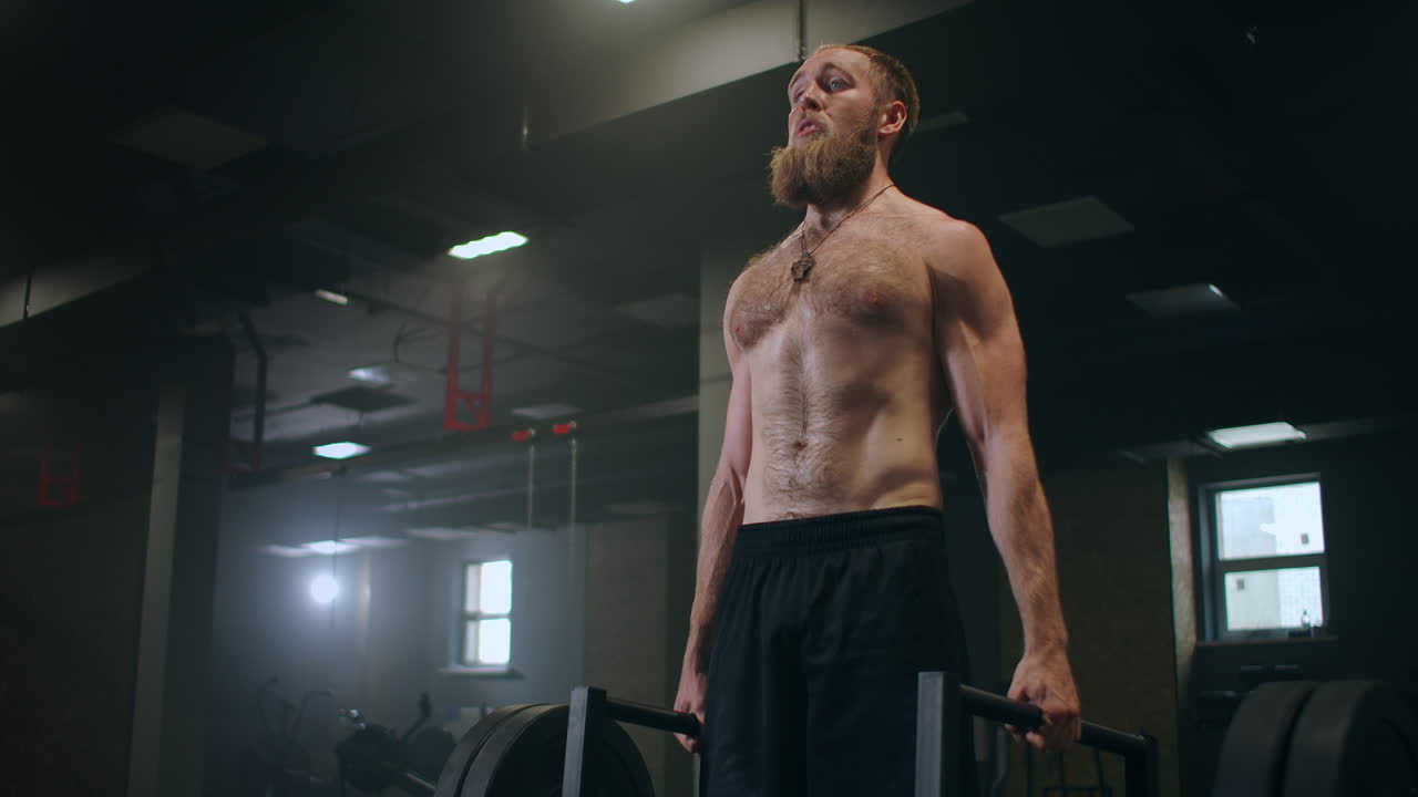 체육적인 아름다운 남자가 체육관에서 바벨로 데드리프트를 합니다. 멋진 남성 프로 보디빌더 운동, 웨이트 리프트 운동, 진정한 피트 트레이닝 시설에서.