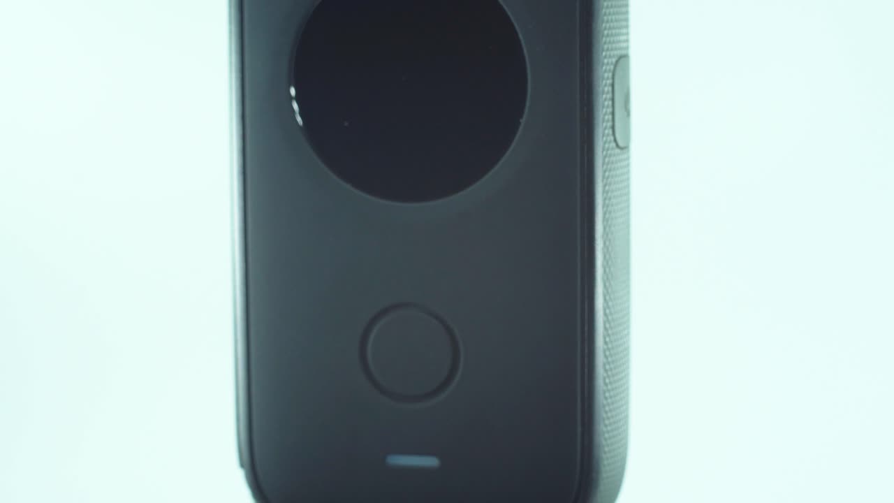 крупный план камеры 360 с двойным объективом, двумя крышками объектива, блестящим студийным отражающим светом, круглым экраном, функциональной кнопкой, на вращающейся подставке, замедленная съемка, видео 4k