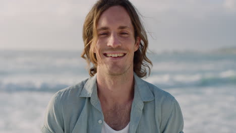 portrait of handsome young man smiling enjoying successful lifestyle running hand throug hair on warm sunny beach seaside background