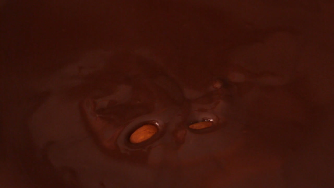 las almendras caen en el chocolate derretido