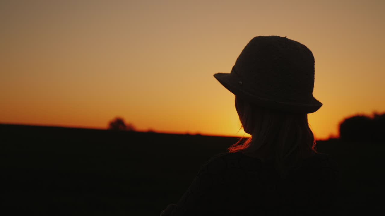 женщина в шляпе смотрит вперед на закат надежда и светлое будущее концепция 4k замедленное видео
