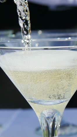 pouring champagne into martini glasses