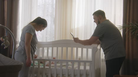 parents taking pictures of their baby in a crib