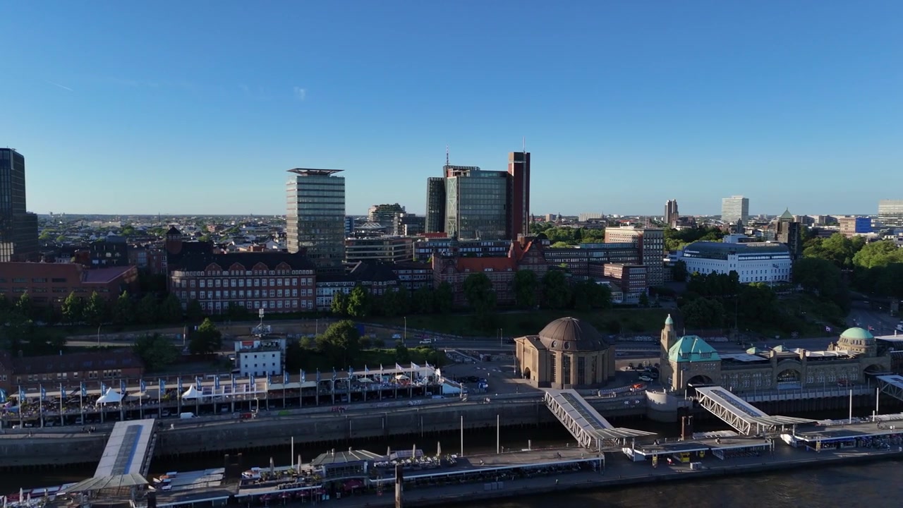 Sanfter Drohnenflug um den runden Landungsbrücken-Turm, der den Hamburger Hafen, Gebäude am Flussufer und die Stadtsilhouette dahinter enthüllt