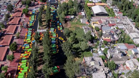 Vista-Aérea-De-Coloridos-Barcos-Tradicionales-En-Un-Canal,-Que-Ofrece-Un-Ambiente-Vibrante-Y-Animado-En-Xochimilco,-México.