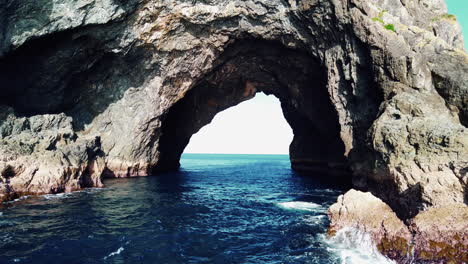 cruise on the famous hole in the rock in motukokako, piercy island in new zealand on a sunny day - medium shot