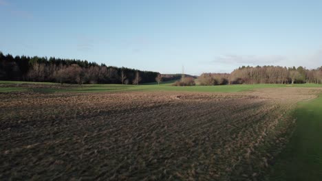 Low-Lever-Drone-Flying,-Field-and-Golf-Course-Surrounded-by-Forest---Dolly-In-Shot