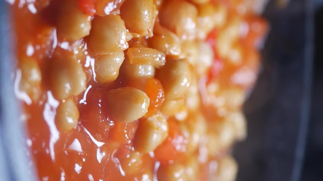 Primo piano di ceci che sobbollono nel sugo di pomodoro rosso