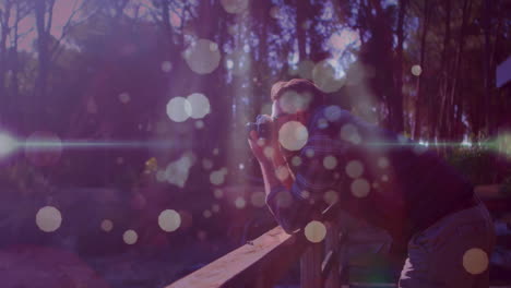 man leaning on railing taking camera shot in park, showing animated lens flare and bokeh graphics
